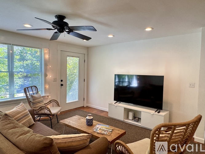 A living room with a brown couch, a television, and a ceiling fan.