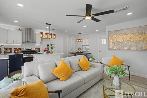 A living room with a grey couch and a ceiling fan.