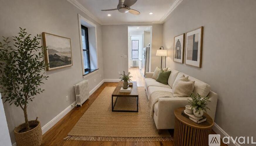 A living room with a couch, a tree, and pictures on the wall.