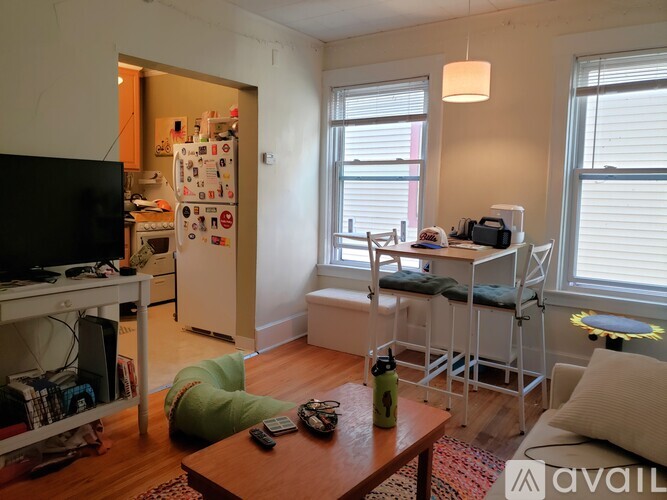 A living room with a refrigerator in the corner.