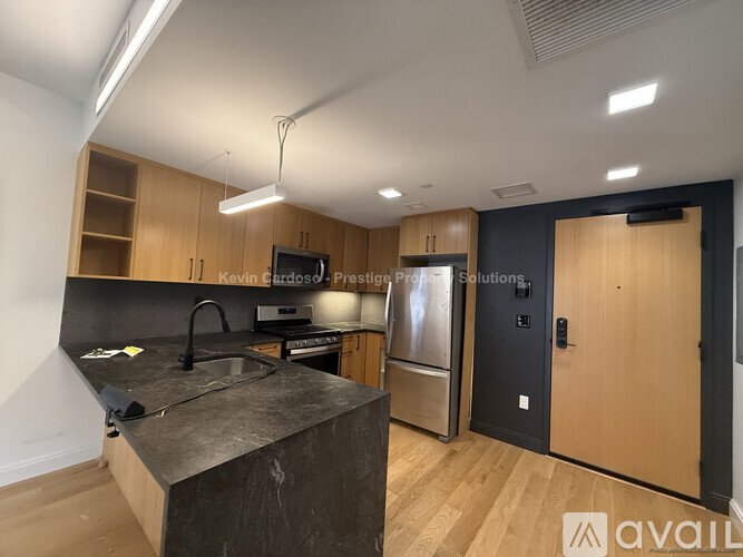 A kitchen with wooden cabinets and a black countertop is available for rent.
