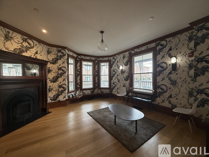 A living room with a fireplace and floral wallpaper.