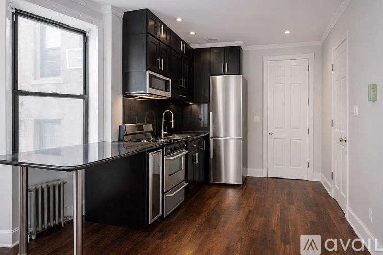 A modern kitchen with black cabinets and stainless steel appliances.
