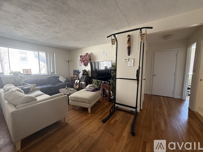 A living room with a couch, chair, and a stand with a flat screen TV on it.