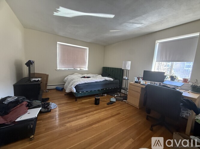 A room with a bed, desk, and suitcase.