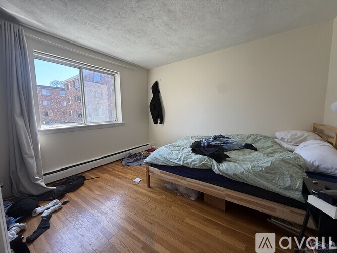 A bedroom with a bed, a window, and a wooden floor.