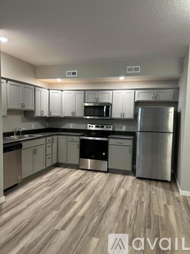 A kitchen with wooden flooring and stainless steel appliances.