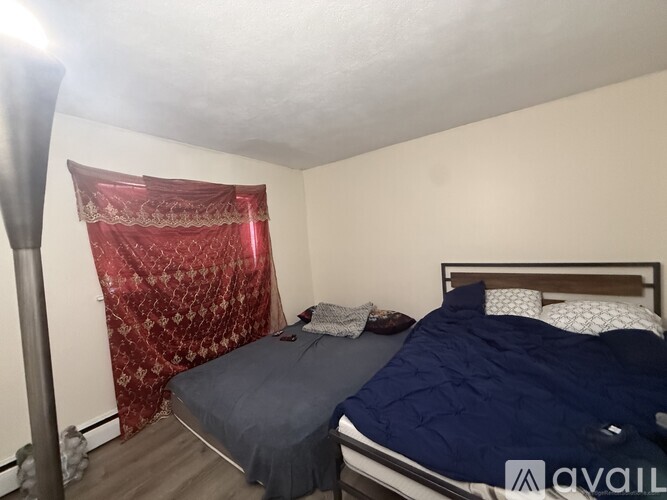 A bedroom with a bed, pillows, and a red curtain.