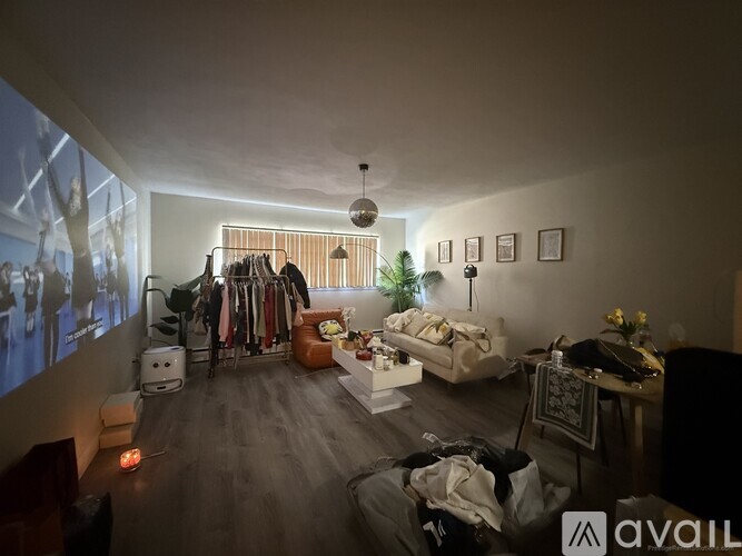 A room with a clothing rack, a couch, a table, and a wall with pictures.
