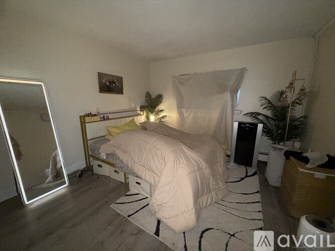 A bedroom with a bed, a mirror, and a plant.