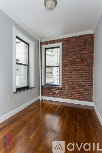 A room with wooden floors and a brick wall.