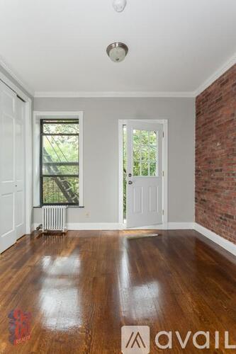 A room with wooden floors and a brick wall.