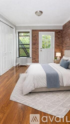 A bedroom with a bed, a window, and a wooden floor.