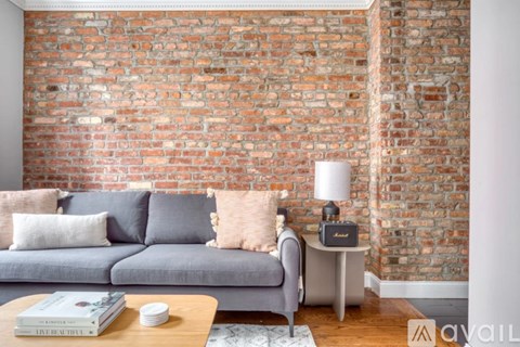 A living room with a grey couch and a brick wall.