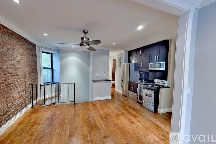 A spacious kitchen with a brick wall and wooden flooring.