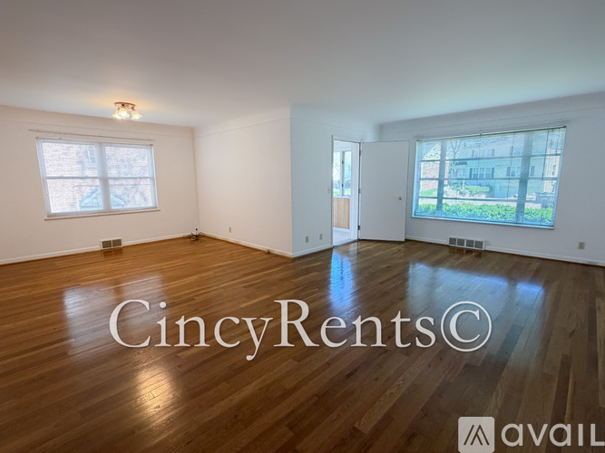 A large empty room with wooden floors and a window.