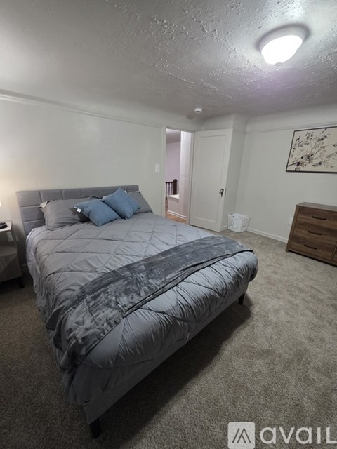 A bedroom with a bed, nightstand, and a painting on the wall.
