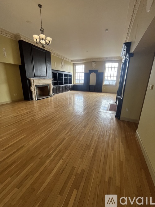 A large empty room with wooden floors and a fireplace.