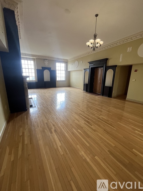 A large empty room with wooden floors and a chandelier.