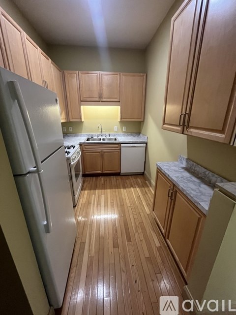 A kitchen with wooden floors and a white refrigerator.