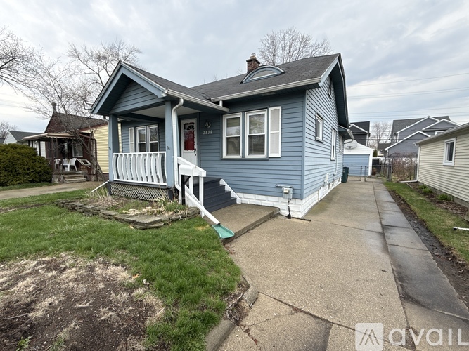 A blue house with a white porch and a sign that says "AVAILABLE".