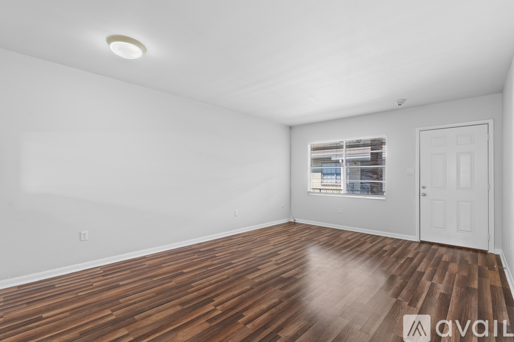 A room with wooden flooring and a window with blinds.