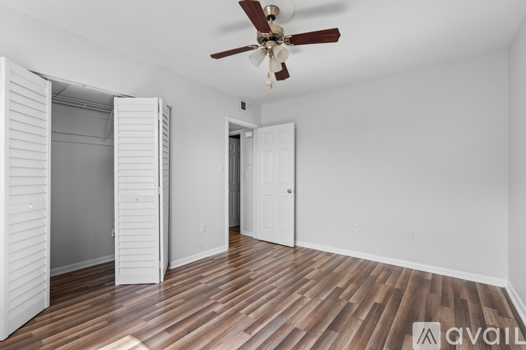A room with a ceiling fan and wooden flooring.