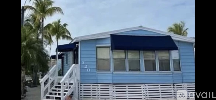 A blue house with a white porch and a black awning.