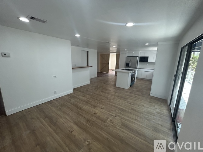 A spacious room with wooden flooring and white walls.