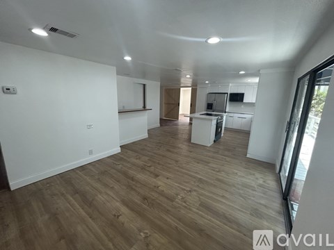 A spacious room with wooden flooring and white walls.