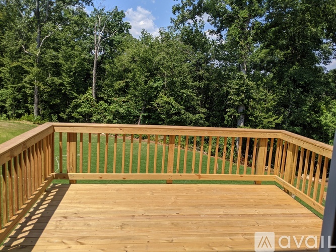 A wooden deck with a railing and trees in the background.