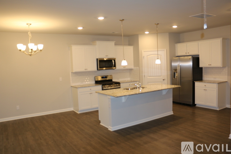 A kitchen with white cabinets and a wooden floor.