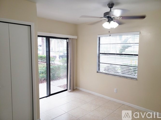 A room with a ceiling fan and sliding glass doors.
