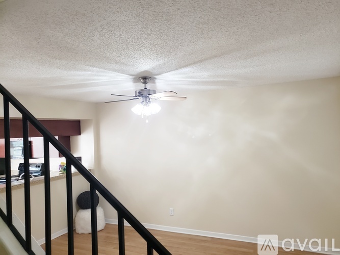 A room with a ceiling fan and a staircase.