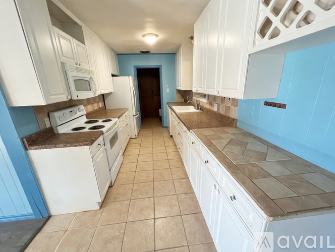 A kitchen with white cabinets and a tiled backsplash.