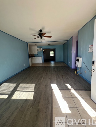 A long hallway with a ceiling fan and light.