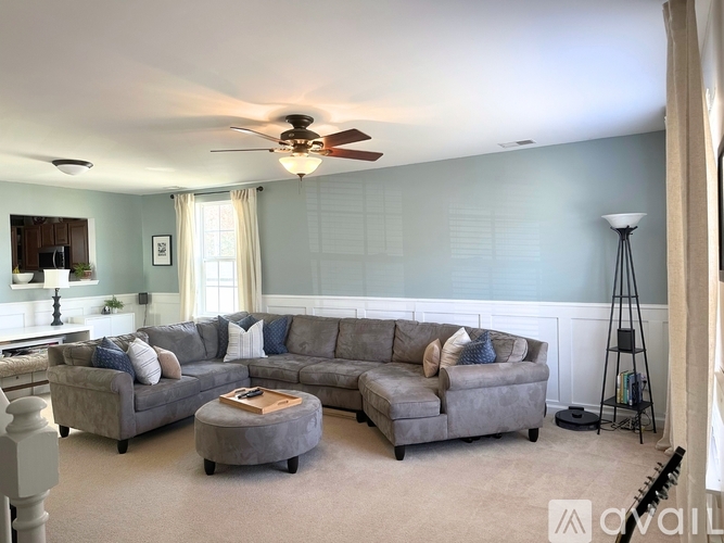 A living room with a grey sectional sofa and a ceiling fan.