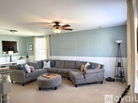 A living room with a grey sectional sofa and a ceiling fan.