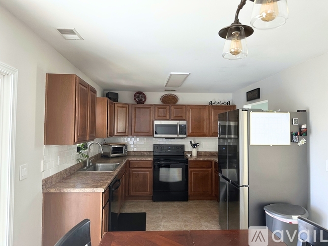 A kitchen with brown cabinets and black appliances.