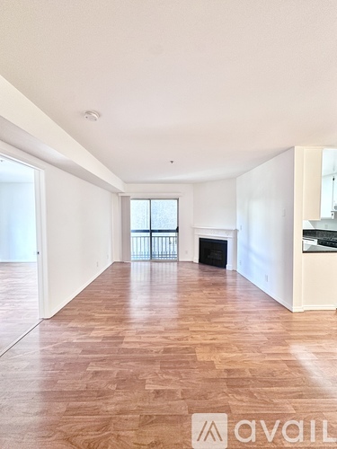 A spacious room with wooden flooring and a fireplace.