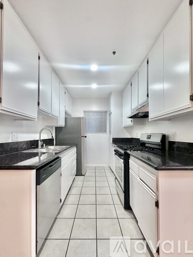 A kitchen with white cabinets and black countertops.