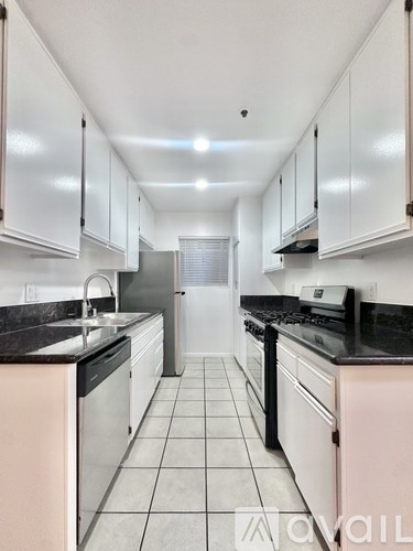 A kitchen with white cabinets and black countertops.
