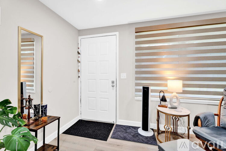 A room with a white door, a table with a lamp, and a plant.