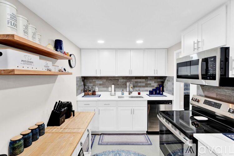 A kitchen with white cabinets and a wooden counter top.
