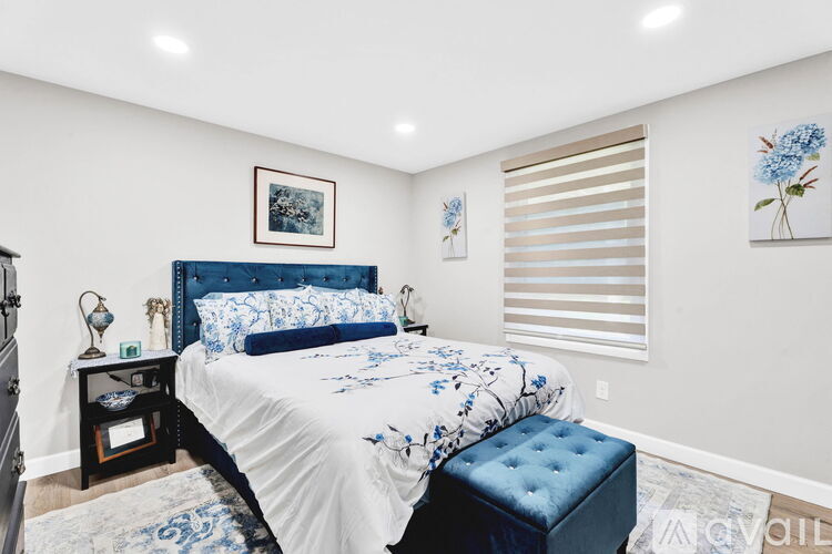 A bedroom with a large bed and a blue ottoman.