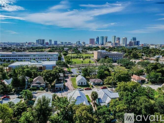 A suburban area with houses and trees in the foreground and a city skyline in the background.