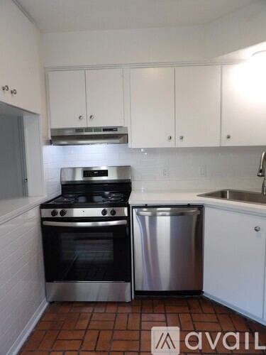 A kitchen with a stove, sink and cabinets.