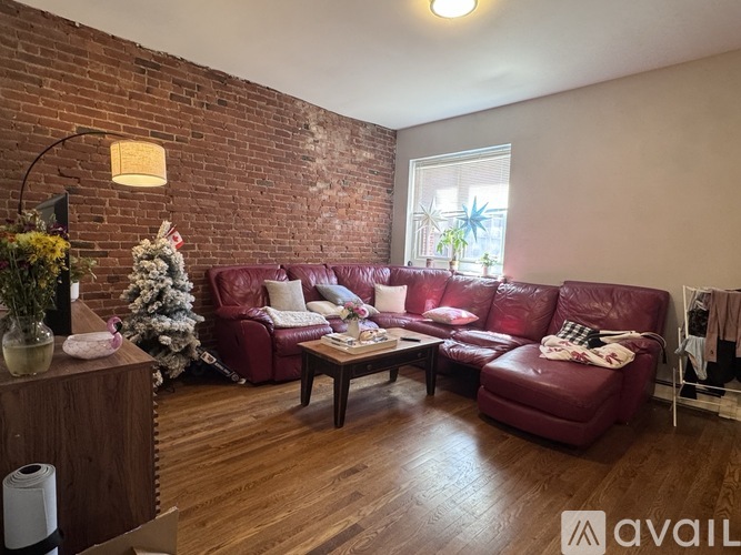 A living room with red leather couches and a wooden floor.