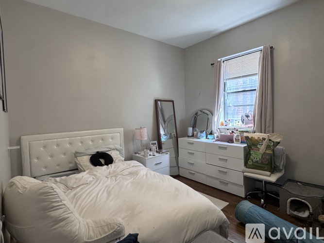 A bedroom with a white bed and a mirror on the wall.
