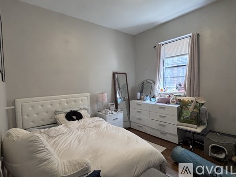 A bedroom with a white bed and a mirror on the wall.